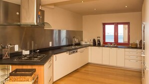 Eine moderne Küche mit Edelstahlgeräten, einem großen Fenster mit Blick und Holzböden.