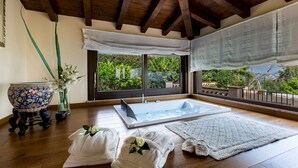A room with a wooden ceiling, a large window with a view of greenery, a bathtub, and towels with flowers. - Villa Alba 12, Emma Villas (Giardini Naxos)