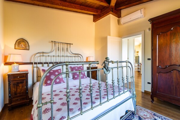 Un dormitorio con estructura de cama metálica, cabecera de madera y una mesita de noche con lámpara.