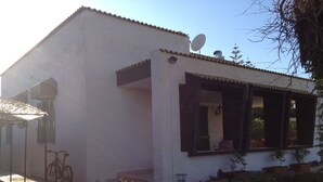 Un edificio blanco con antena parabólica, una bicicleta y macetas.