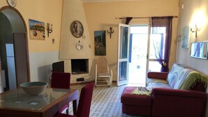 Una sala de estar con chimenea, una mesa de comedor con sillas, un sofá y vistas al exterior a través de una puerta.