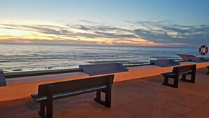 A seaside bench area with a lifebuoy and a view of the ocean at sunset. - T2 by the beach, with pool, WIFI and cable TV, in Praia do Pedrogão (Coimbrão)