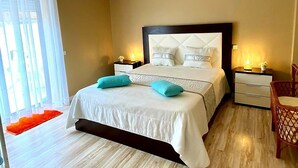 A bedroom with a large bed, two bedside tables, a chair, and a window with curtains. - T2 by the beach, with pool, WIFI and cable TV, in Praia do Pedrogão (Coimbrão)