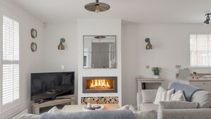 Een moderne woonkamer met een open haard, een televisie en een eethoek.