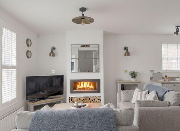 Een moderne woonkamer met een open haard, een televisie en een eethoek.