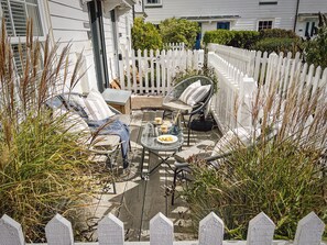A patio with outdoor furniture, a white picket fence, and a house in the background.