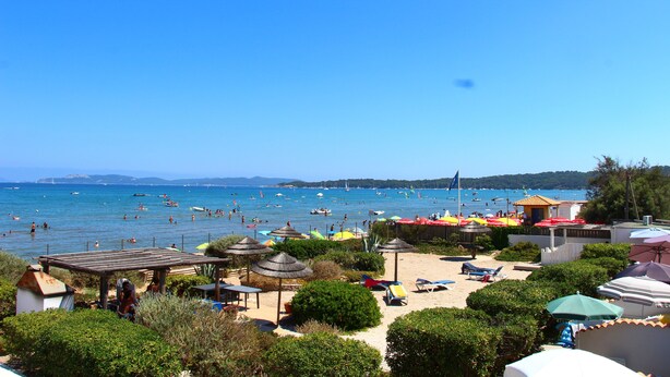 A beach with umbrellas, lounge chairs, and a view of the sea. - Waterfront duplex 150m2 12/14 pax, magnificent sea view. (Hyères)