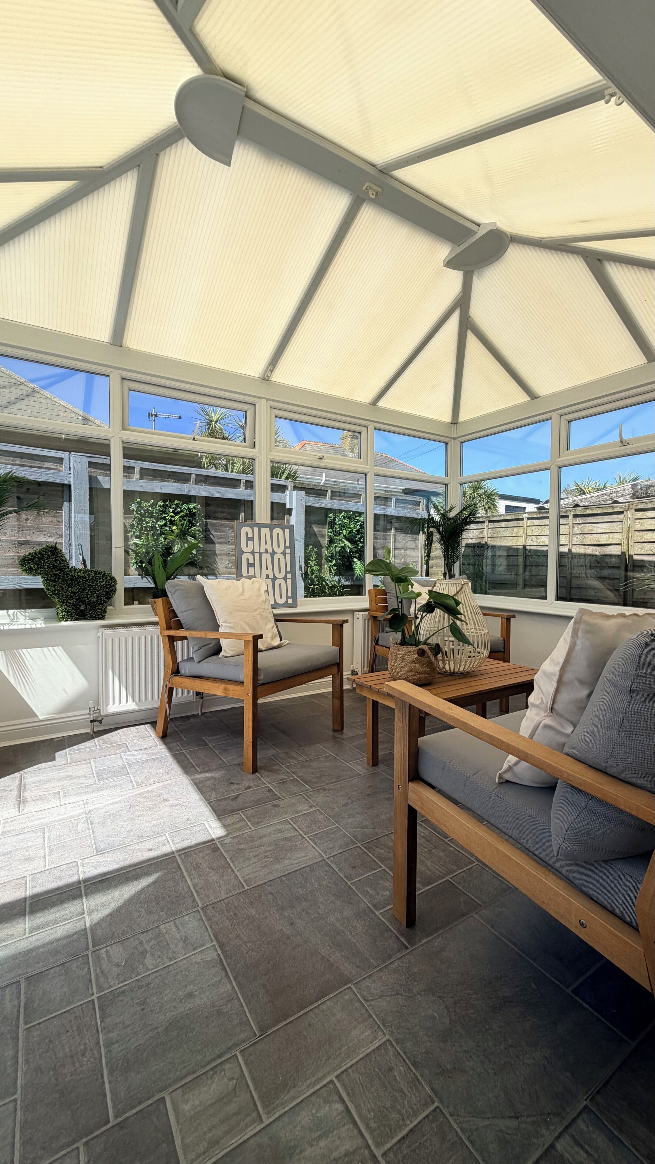 A sunroom with a high ceiling, large windows, and a view of the outside.