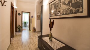 A hallway with a marble floor, a dark wooden dresser, a framed artwork, and a vase with dried plants. - Alghero Apartment Cervi 30 meters from Alghero beach for 6 persons (Alghero)
