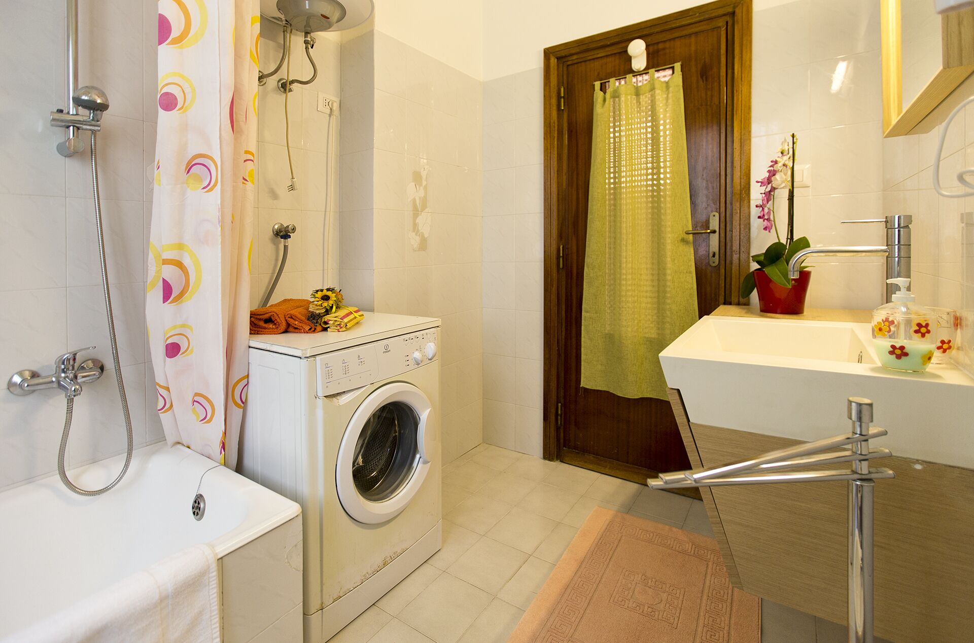 A bathroom with a washing machine, a bathtub, a shower, a sink, and a mirror.