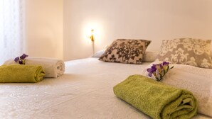 A neatly made bed with rolled towels and a flower, a bedside lamp, and patterned pillows. - Alghero Apartment Cervi 30 meters from Alghero beach for 6 persons (Alghero)