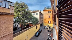 A narrow street with parked cars and a tree on the left.