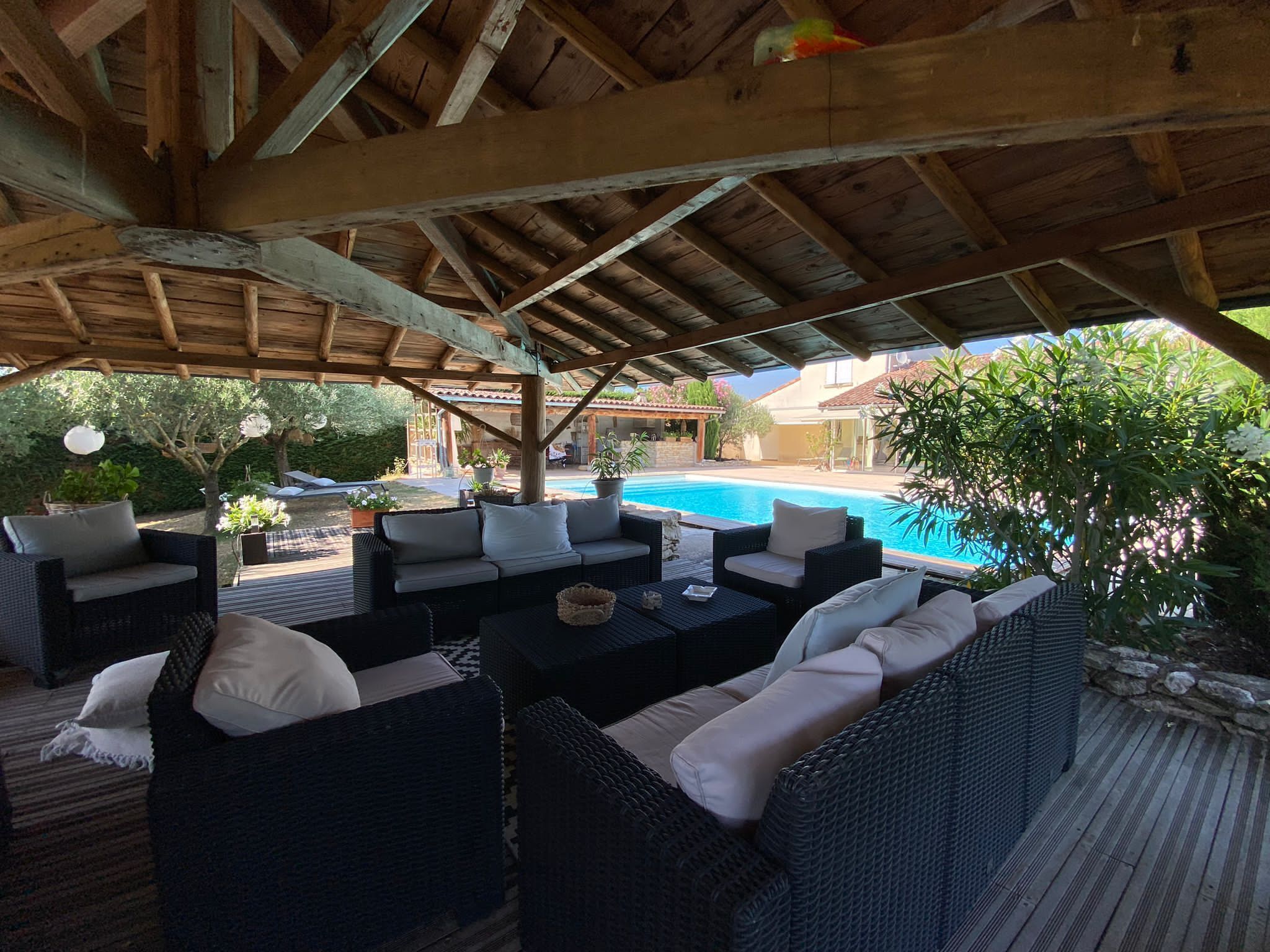 An outdoor patio with wicker furniture and a pool.