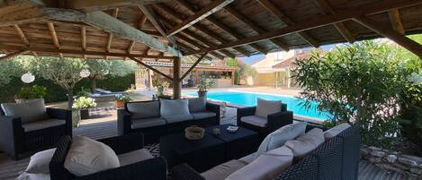 An outdoor patio with wicker furniture and a pool.