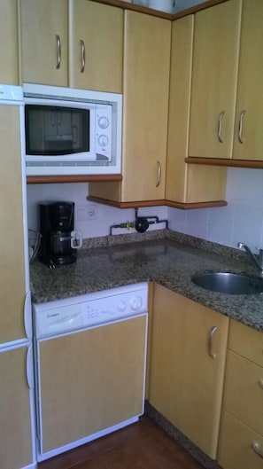 A compact kitchen with a microwave, coffee maker, and dishwasher.