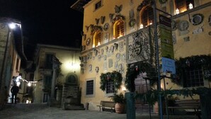 Un edifici històric amb façanes de pedra, nombroses finestres i zones d'seure a l'exterior.