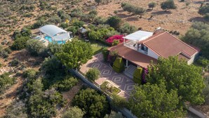 Vue aérienne d’une propriété dotée d’une piscine, d’un patio couvert et d’une maison avec un toit en tuiles.