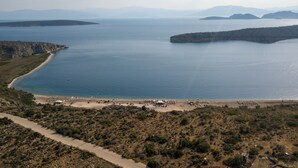 Un paysage côtier avec une plage, une route et des montagnes à l’horizon.