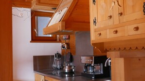 A compact kitchen with wooden cabinets, a built-in stove, and a coffee machine.