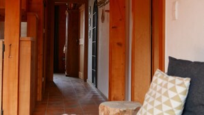A wooden interior hallway leading to a bedroom with a bed and a nightstand.