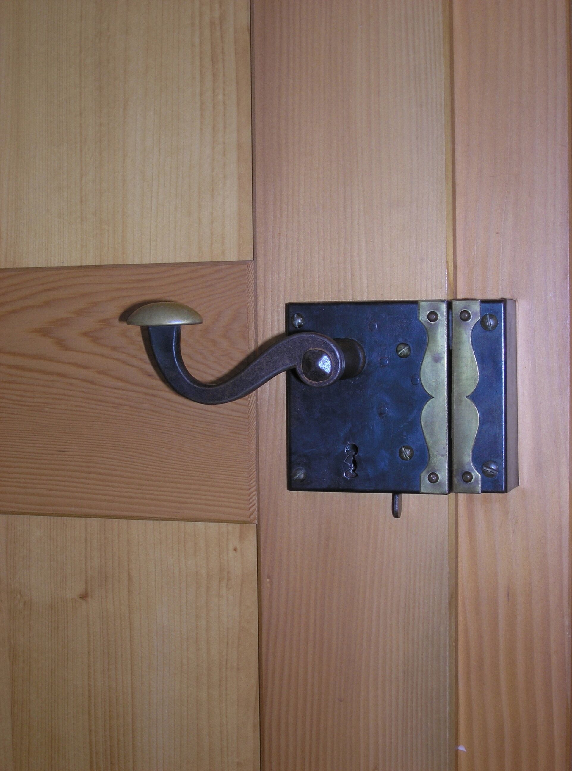 A wooden door with a metal latch and a curved handle.