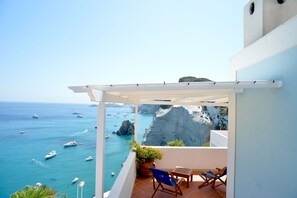 Un balcon avec vue sur la mer et les bateaux, une pergola blanche et une plante en pot.