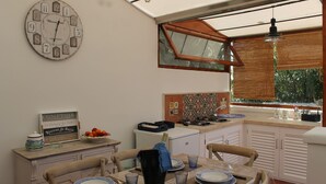 A compact kitchen with a dining area, a clock, and a view through a window.