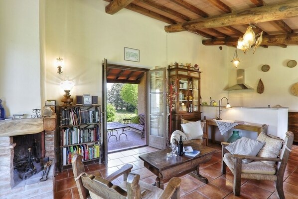 Una sala de estar rústica con chimenea, una estantería, un comedor y vistas al jardín.