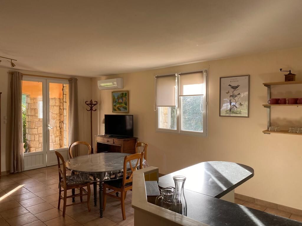 A dining area with a table and chairs, a television, and a window with curtains.