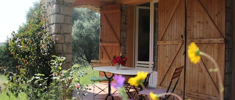 Un patio al aire libre con una mesa redonda y sillas, rodeado de muros de piedra y puertas de madera.