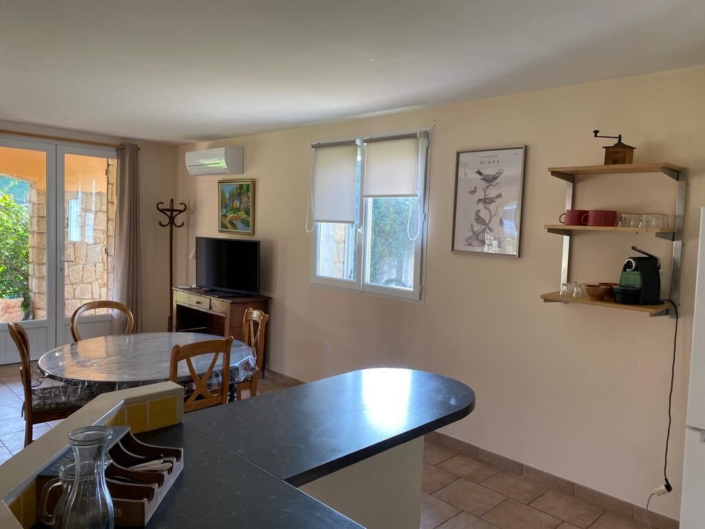 A kitchen with a dining table, chairs, a TV, and a coffee machine.