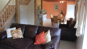 Un soggiorno con un divano in pelle marrone, una zona pranzo e una cucina sullo sfondo.