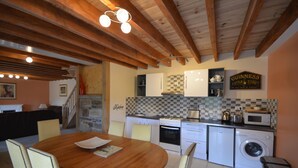 Una cucina con travi in legno, un tavolo da pranzo, sedie, una lavatrice e un forno a microonde.