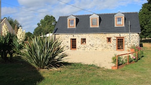 Una casa in pietra con tetto spiovente, due piccole finestrelle a lucernario e una porta in legno.