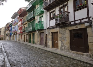 Una calle empedrada flanqueada por edificios coloridos, cada uno con estilos arquitectónicos diferentes y balcones.