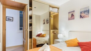 Een hotelkamer met een bed, een kledingkast, een nachtkastje en een spiegel.