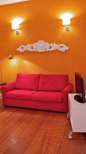Relax in a stylish space with a vibrant wall, a cozy sofa, and a TV for entertainment.
