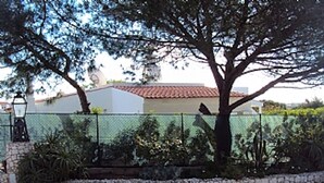 Una casa con un camino de piedra, una cerca y un árbol.