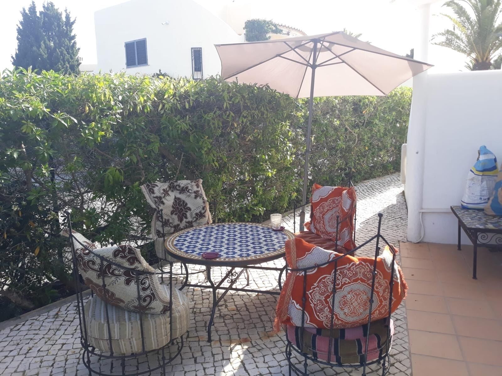 Um pátio ao ar livre com uma mesa redonda, duas cadeiras e um grande guarda-sol.