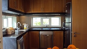 Cocina moderna con armarios de madera, un refrigerador de acero inoxidable y una ventana que proporciona luz natural.