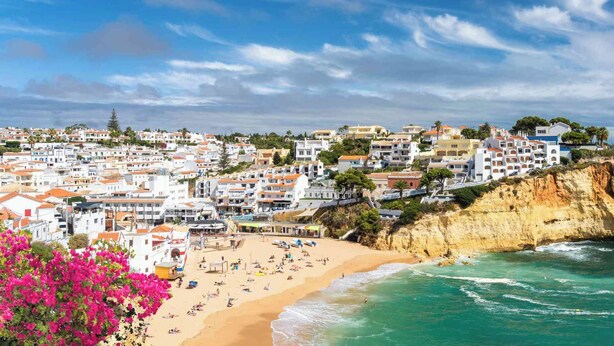 Un pueblo costero con playa, edificios y un acantilado.