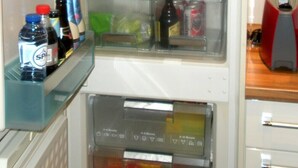 Un réfrigérateur ouvert, dont les étagères contiennent divers aliments et boissons.