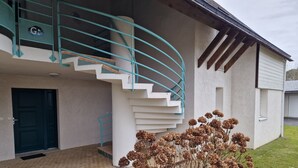A modern building with a spiral staircase, a door, and a garden with dried flowers. - Apartment La Mouette Rated 3* (Saint-Philibert)