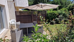 An outdoor patio with a table and chairs, surrounded by greenery and a wooden fence. - Apartment La Mouette Rated 3* (Saint-Philibert)