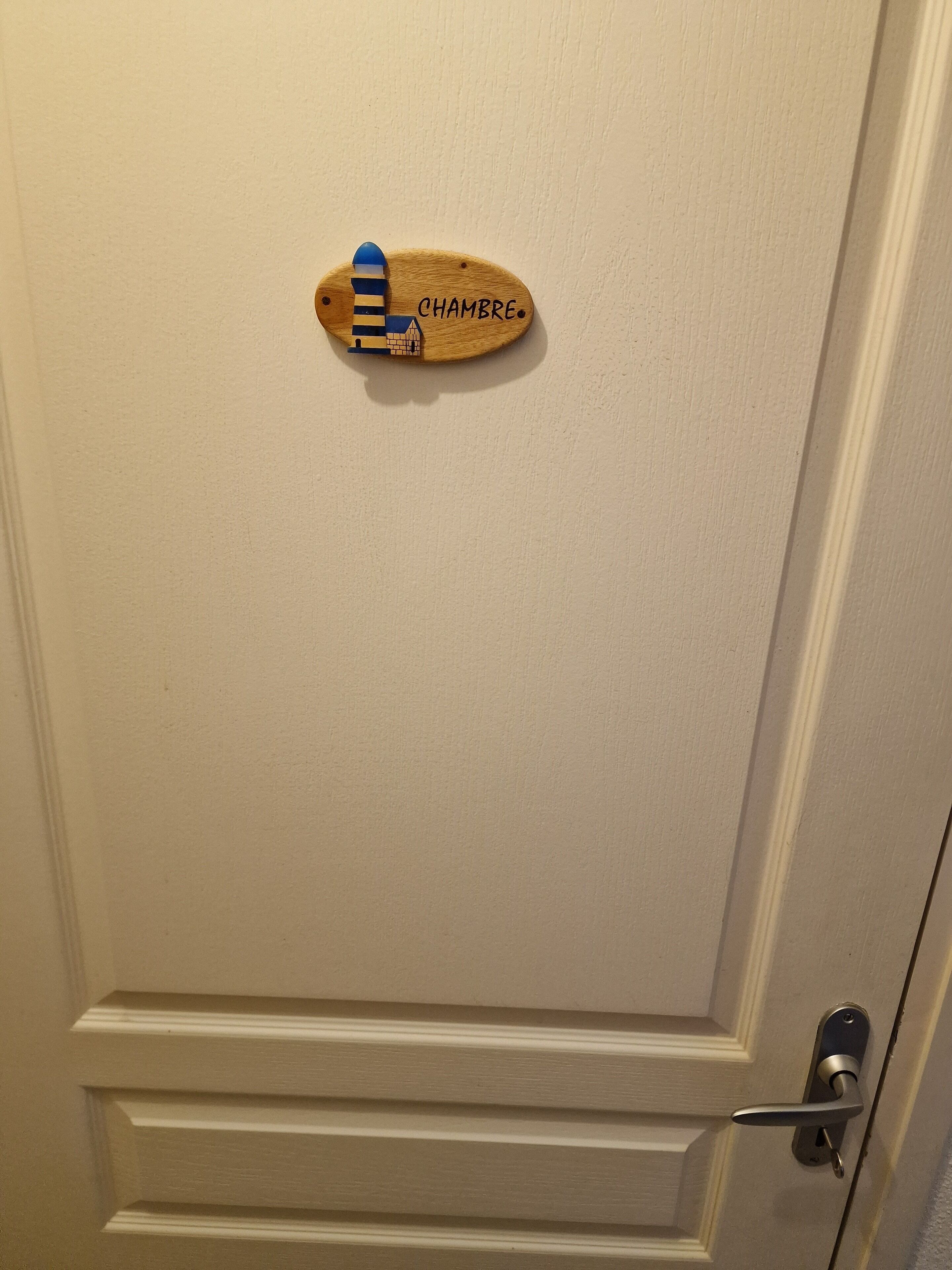A door with a wooden plaque that reads 'CHAMBRE.'