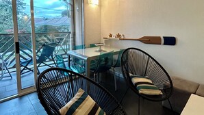 A dining area with a table and chairs, a sliding glass door leading to an outdoor space, and a wall-mounted light fixture.