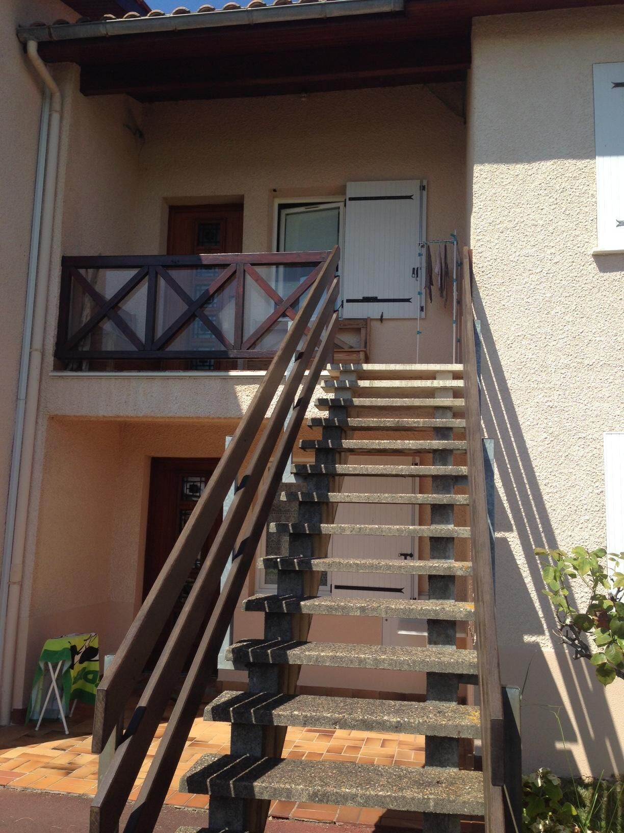 Una escalera con barandilla de madera que lleva a un balcón en el segundo piso.