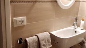 A bathroom with a white sink, a mirror, and a towel hanging on a rack.
