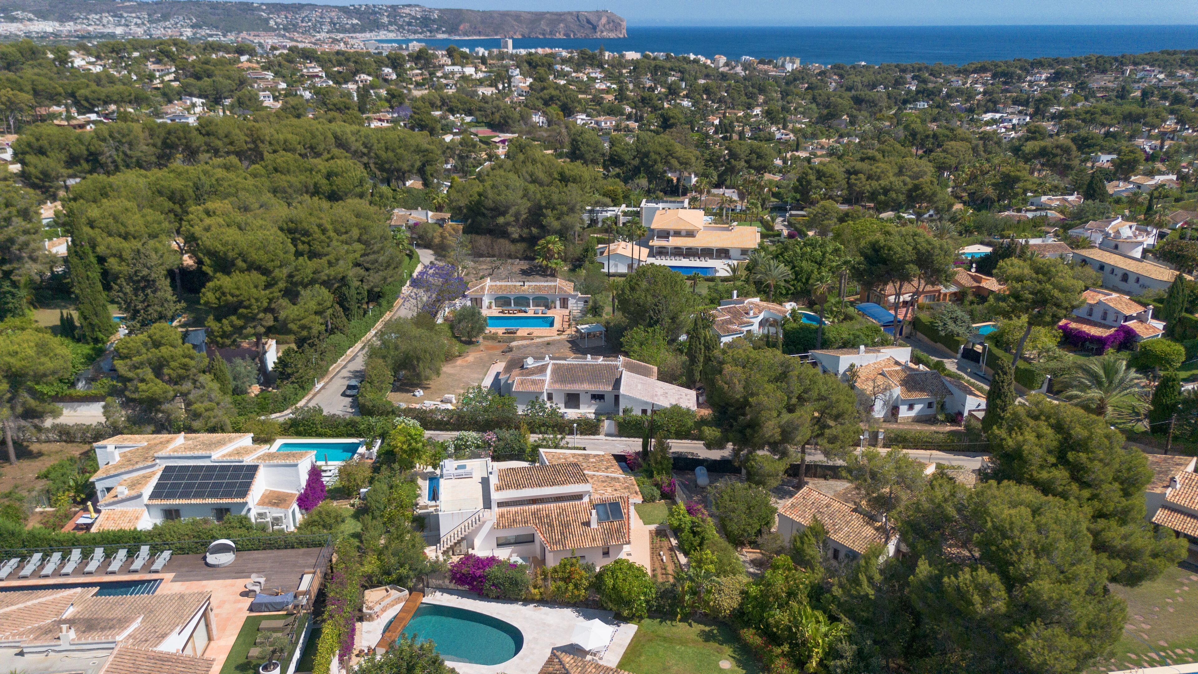 Vista aérea de una zona residencial con casas, una piscina y un acantilado frente al mar.