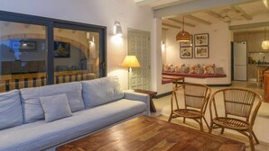 A modern living room with a sofa, chairs, and a coffee table. There is a dining area with a table and chairs. The room has a large window and a ceiling fan. - New house: Heated swimming pool, large BBQ, 100MB wifi, air conditioning (Tosalet, El (Javea/Xabia))